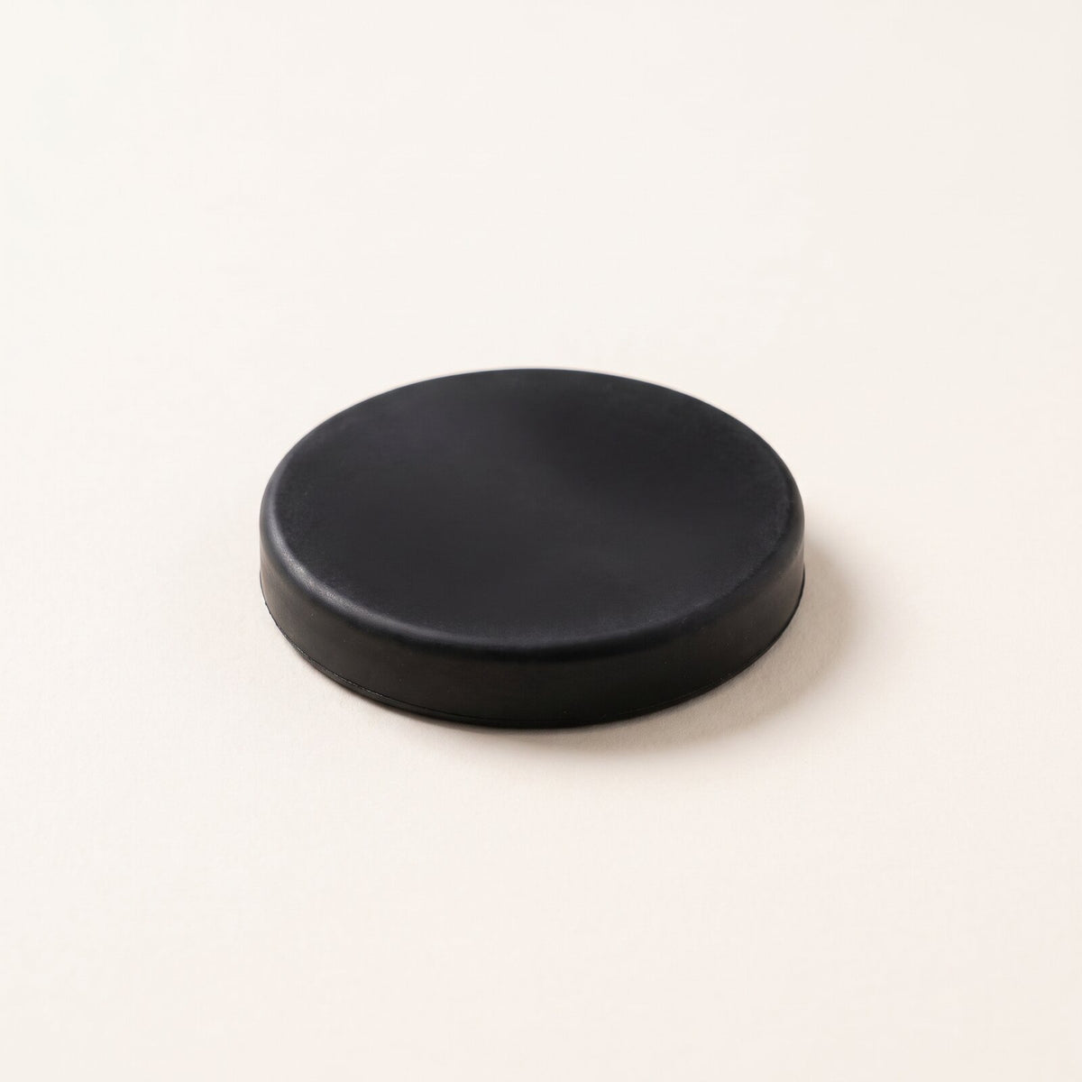 A black striking puck lying on warm paper.