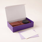 The gift box open, with the folded case and the striking puck inside and a blank note card on an envelope in front.