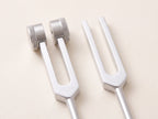 Close-up of a weighted fork with round knurled weights beside a plain fork with bare prongs.